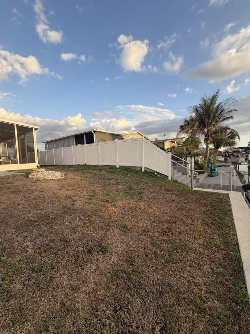 White vinyl privacy fence across backyard with palm trees